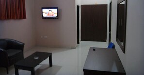 A living room with a television, a sofa, a coffee table, and a wardrobe.