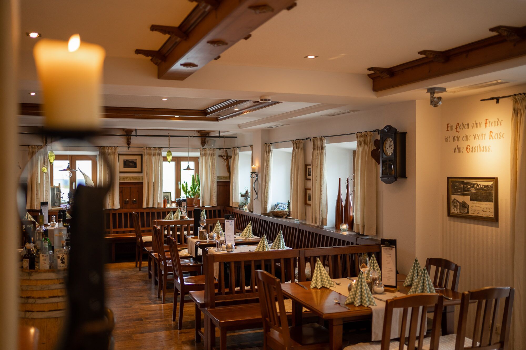 Un restaurante con muebles de madera, una barra larga y una vela en la mesa.