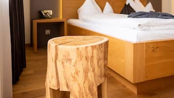 Un dormitorio moderno con estructura de cama de madera, una mesita de noche y un pequeño taburete de madera.