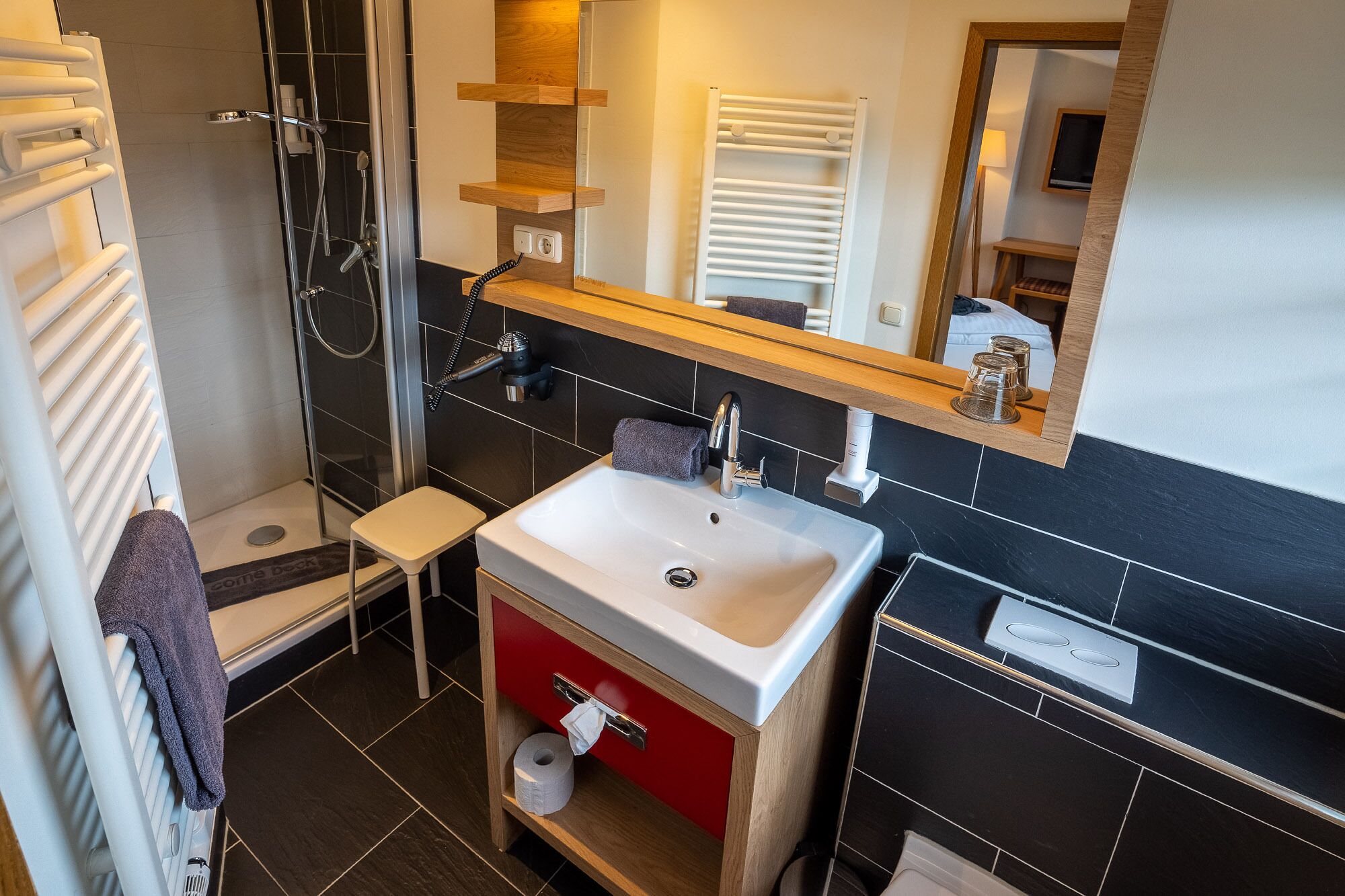 A modern bathroom with a shower, a sink, a toilet, and a mirror.