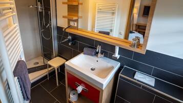 A modern bathroom with a shower, a sink, a toilet, and a mirror.