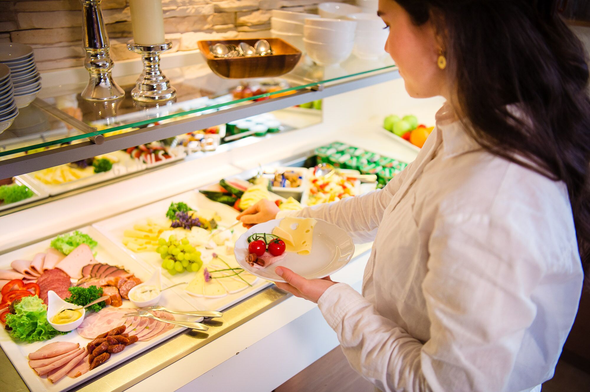 A buffet with various food items including meats, cheeses, and fruits.