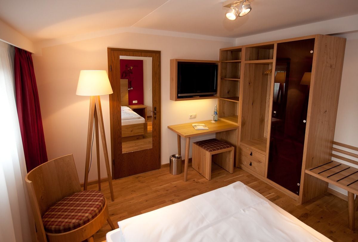 Une chambre d’hôtel comprenant un lit, un bureau avec une chaise, une télévision, une armoire et une lampe.