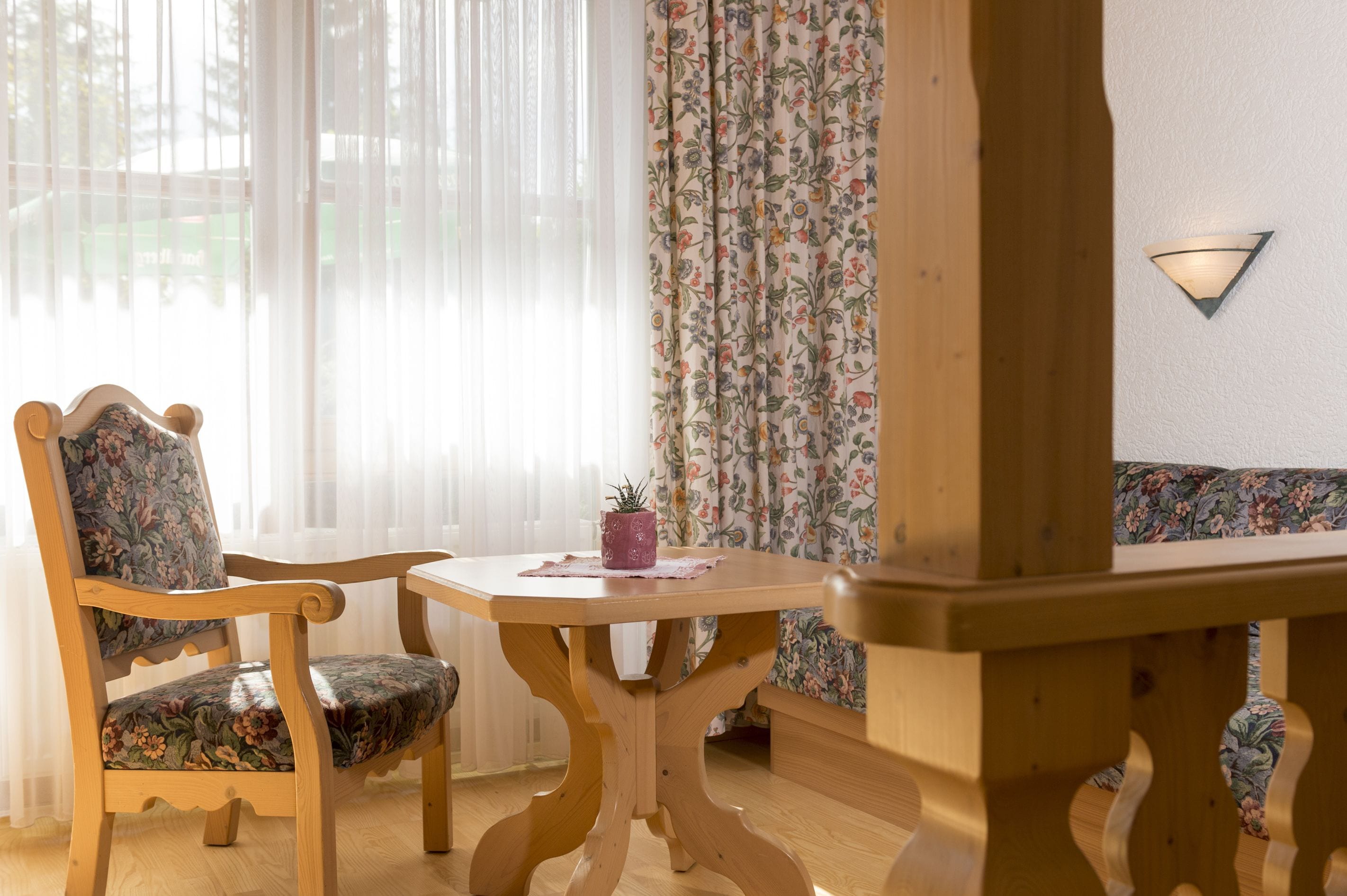 Una mesa de madera para comer con una silla, una planta pequeña en maceta y una lámpara fijada a la pared.