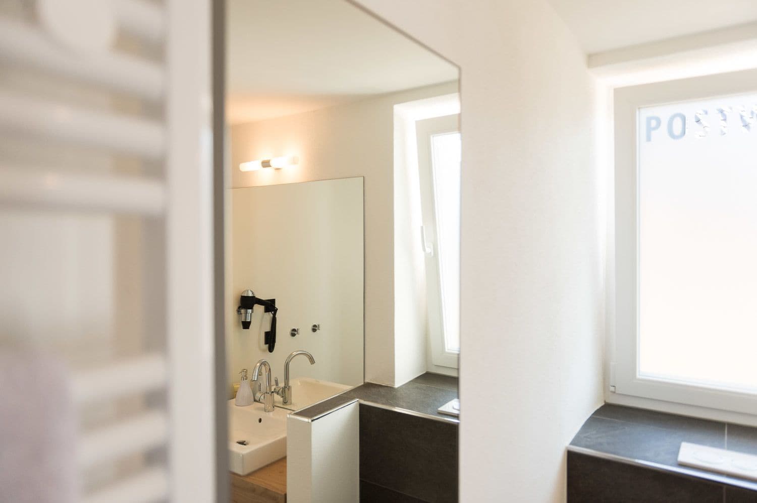 A modern bathroom with a large mirror, a sink, and a shower.