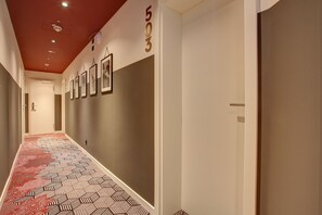 Un pasillo con alfombra estampada, techo rojo y una puerta con el número 503.