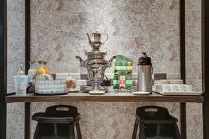 Una zona de bar con una máquina de café, una olla grande de plata y varios dispensadores de bebidas.