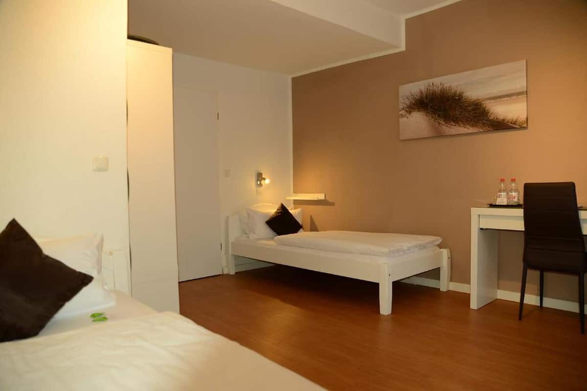 A small, clean room with a bed, a desk, and a chair.