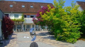 A courtyard with a stone sculpture, a pergola, and a building with a tiled roof. - Hotel Herrenhof (Lübeck)