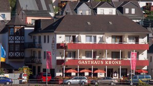 Ein Hotel namens GASTHAUS KRONE mit einer markanten roten Fassade, mehreren Balkonen und Blick auf den Fluss.