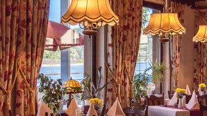 Ein Restaurant mit gedeckten Tischen, floralen Vorhängen und hängenden Lampen.
