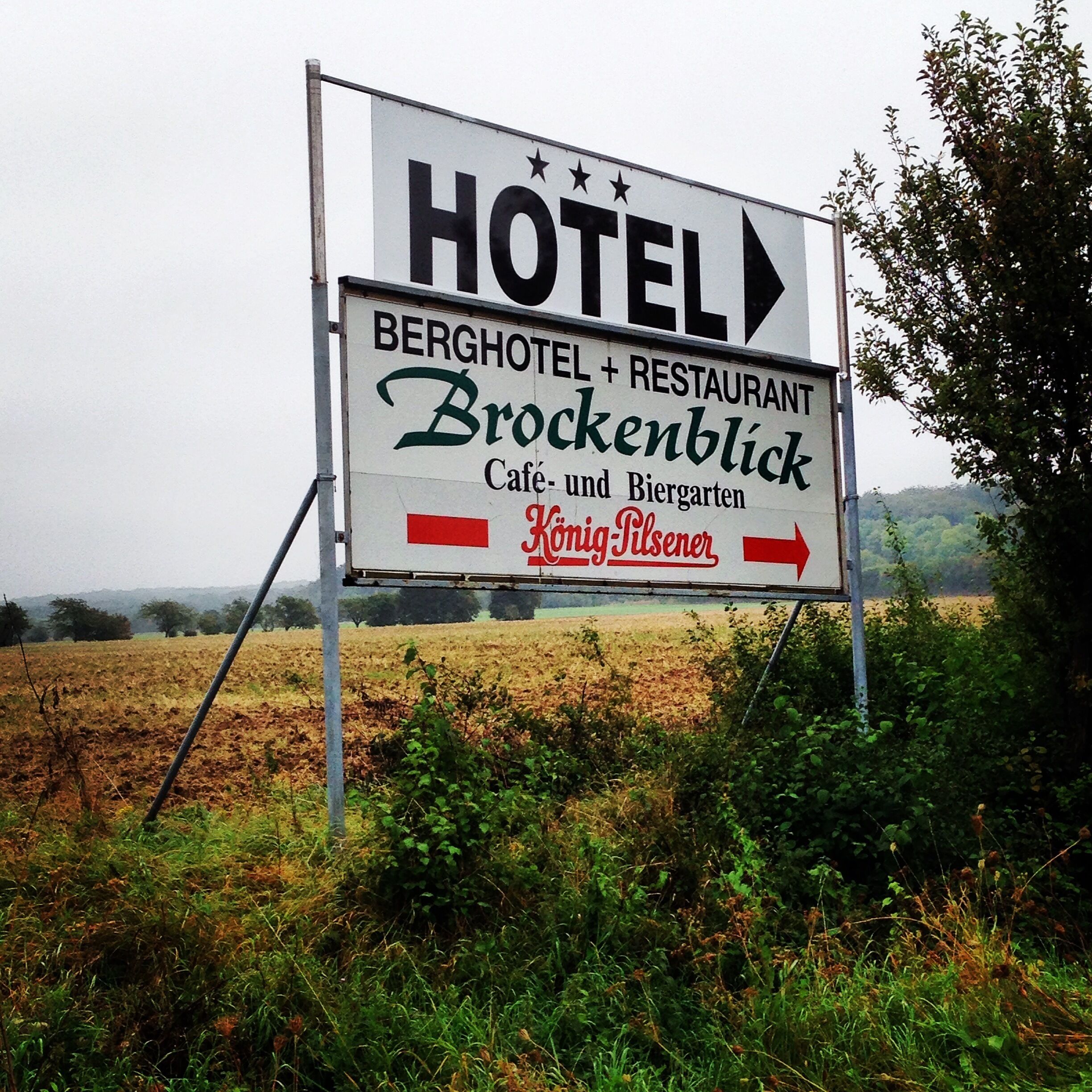 Señal de hotel y restaurante llamado "BERGHOTEL + RESTAURANT Bockenblick" con una flecha direccional apuntando a la derecha.