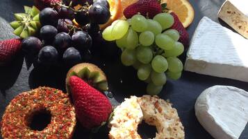 A selection of fruits and cheeses on a slate board.