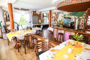 A restaurant with wooden tables, chairs, and a bar area.