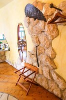 A stone wall with a wooden chair and a coat rack.