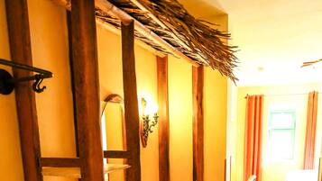 A hallway with wooden shelves, a stone-tiled floor, and a bed in the distance.