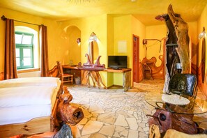 A room with a bed, a desk with a television, and a unique wooden sculpture. - Backstage Hotel (Dresden)