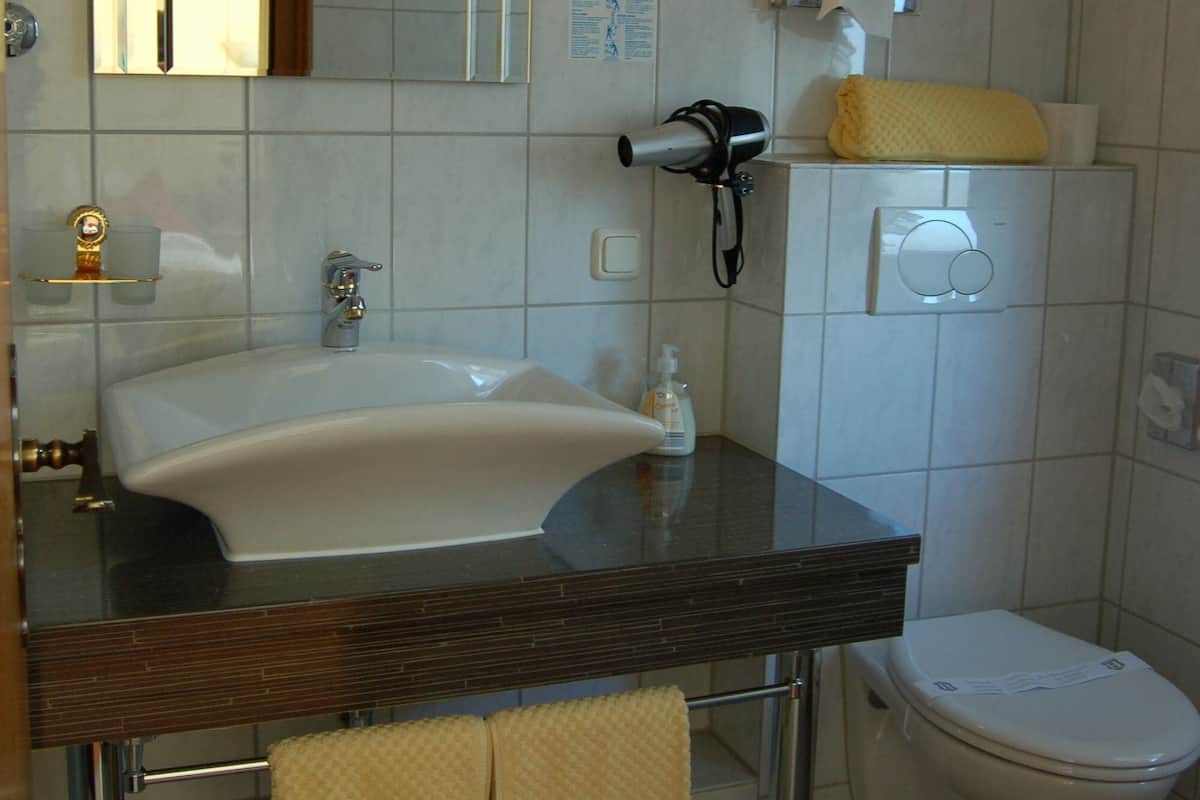 A bathroom with a sink, mirror, towel rack, and toilet.
