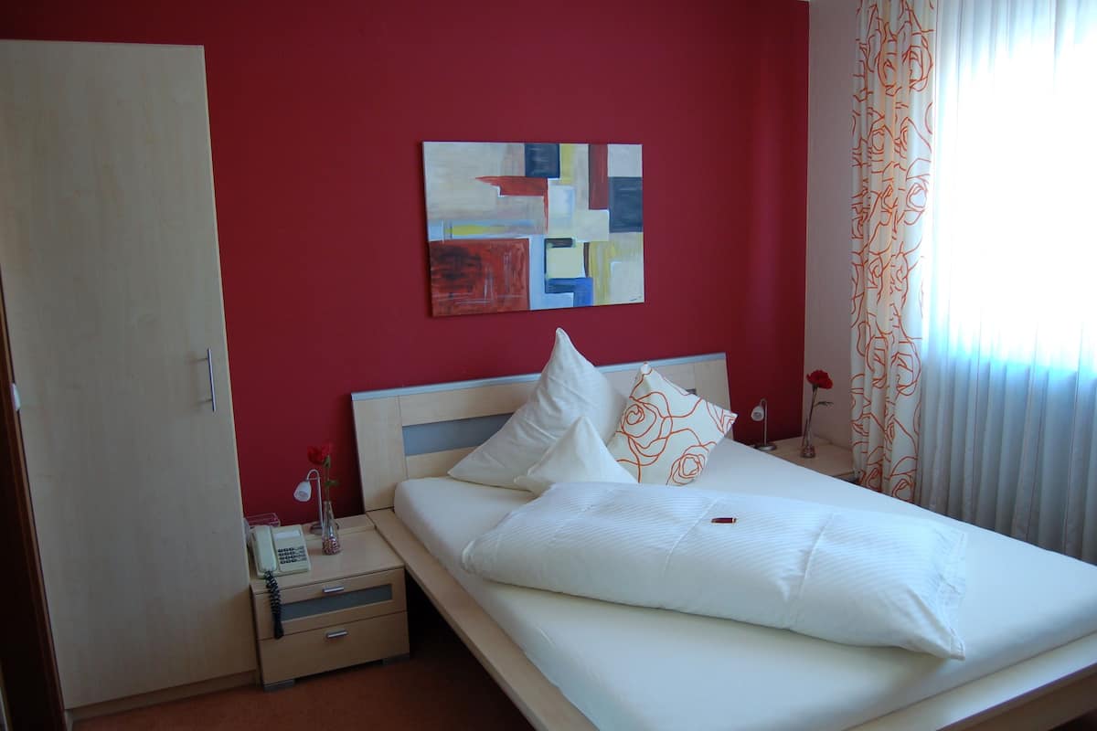 A hotel room with a bed, a nightstand, a phone, and a painting on the wall.