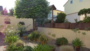 A courtyard with potted plants, a tree, and a building with a staircase. - Hotel Zur Linde (Hanau)