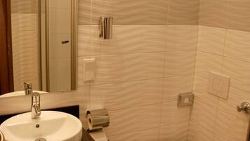 Une salle de bain équipée d’un lavabo, d’un miroir, de toilettes et d’une douche.