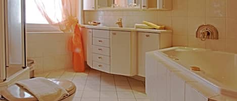 Un baño con inodoro, lavamanos y bañera, que incluye un espejo grande y una ventana con cortinas.