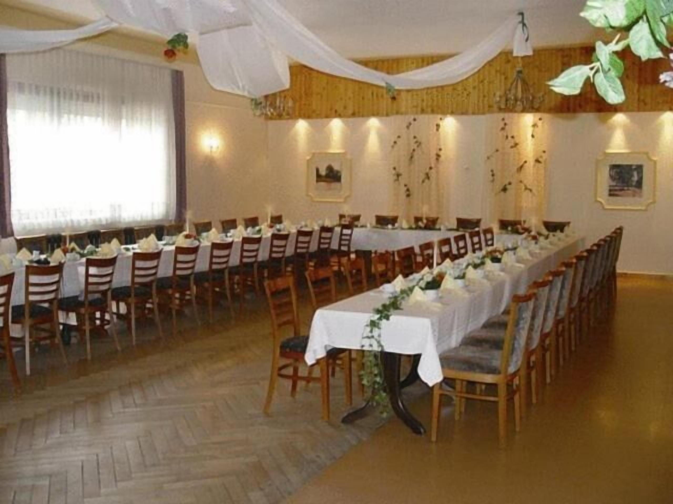A long dining table with chairs, white tablecloths, and floral centerpieces.
