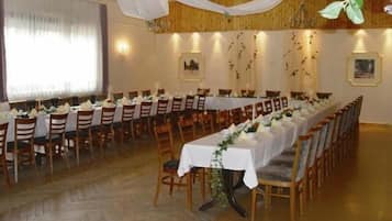A long dining table with chairs, white tablecloths, and floral centerpieces.