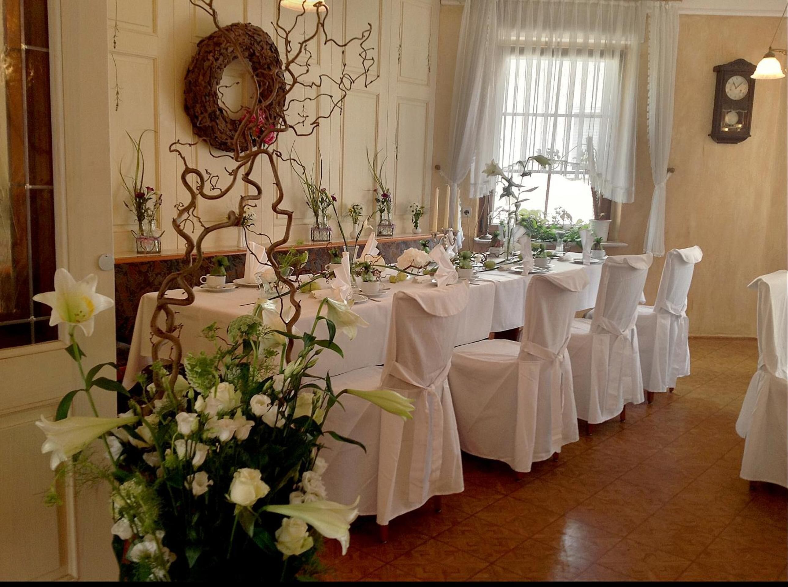 A formal dining room with white tablecloths, chairs, and floral centerpieces.