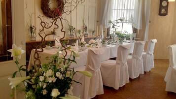 A formal dining room with white tablecloths, chairs, and floral centerpieces.