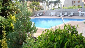 A swimming pool surrounded by greenery and white lounge chairs. - Hotel Torres Touriño (Sanxenxo)