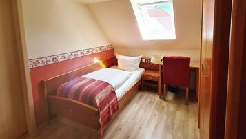 Un dormitorio con cama, escritorio y silla.