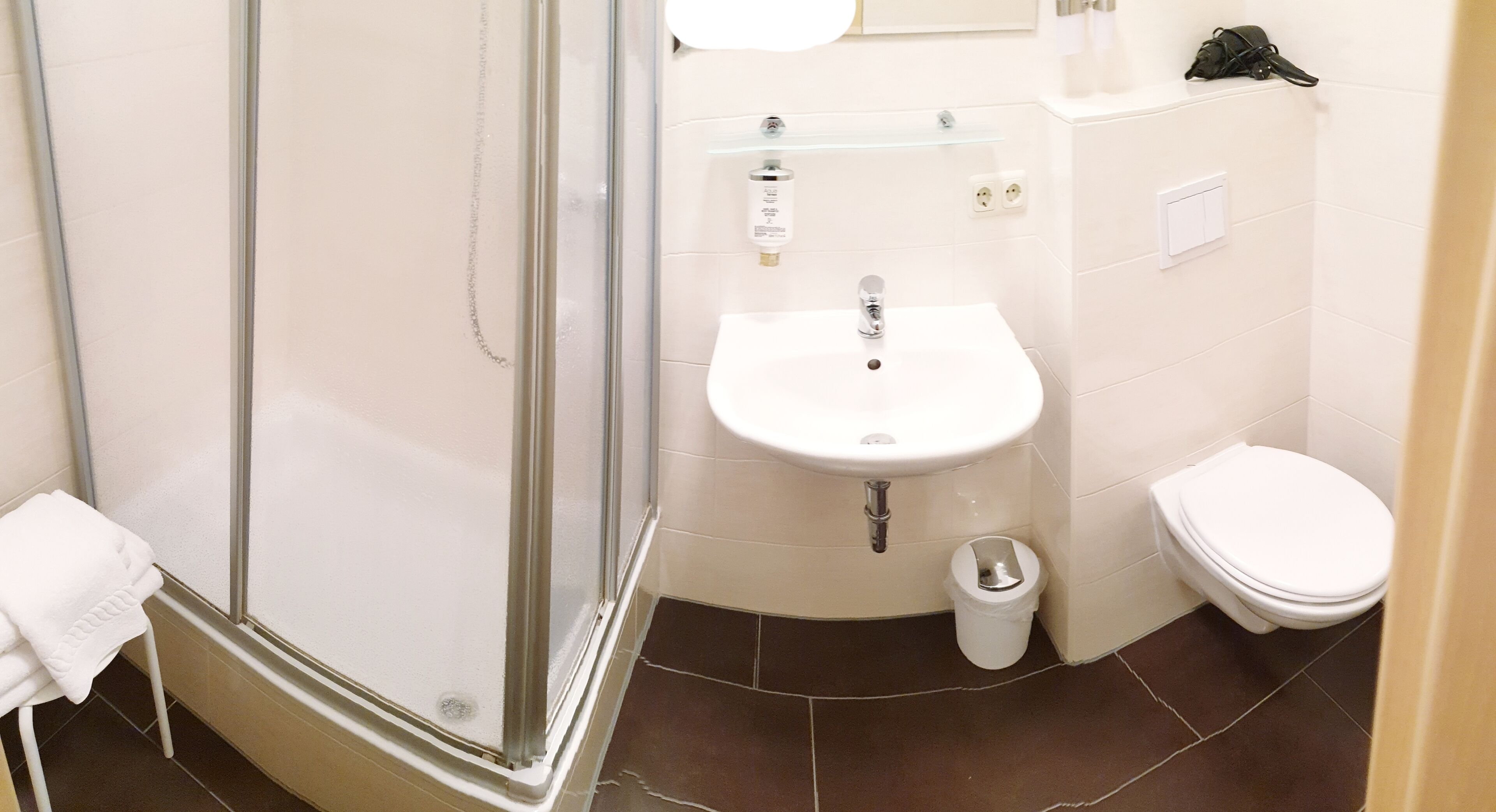 Un baño con cabina de ducha de vidrio, un lavabo blanco y un inodoro.