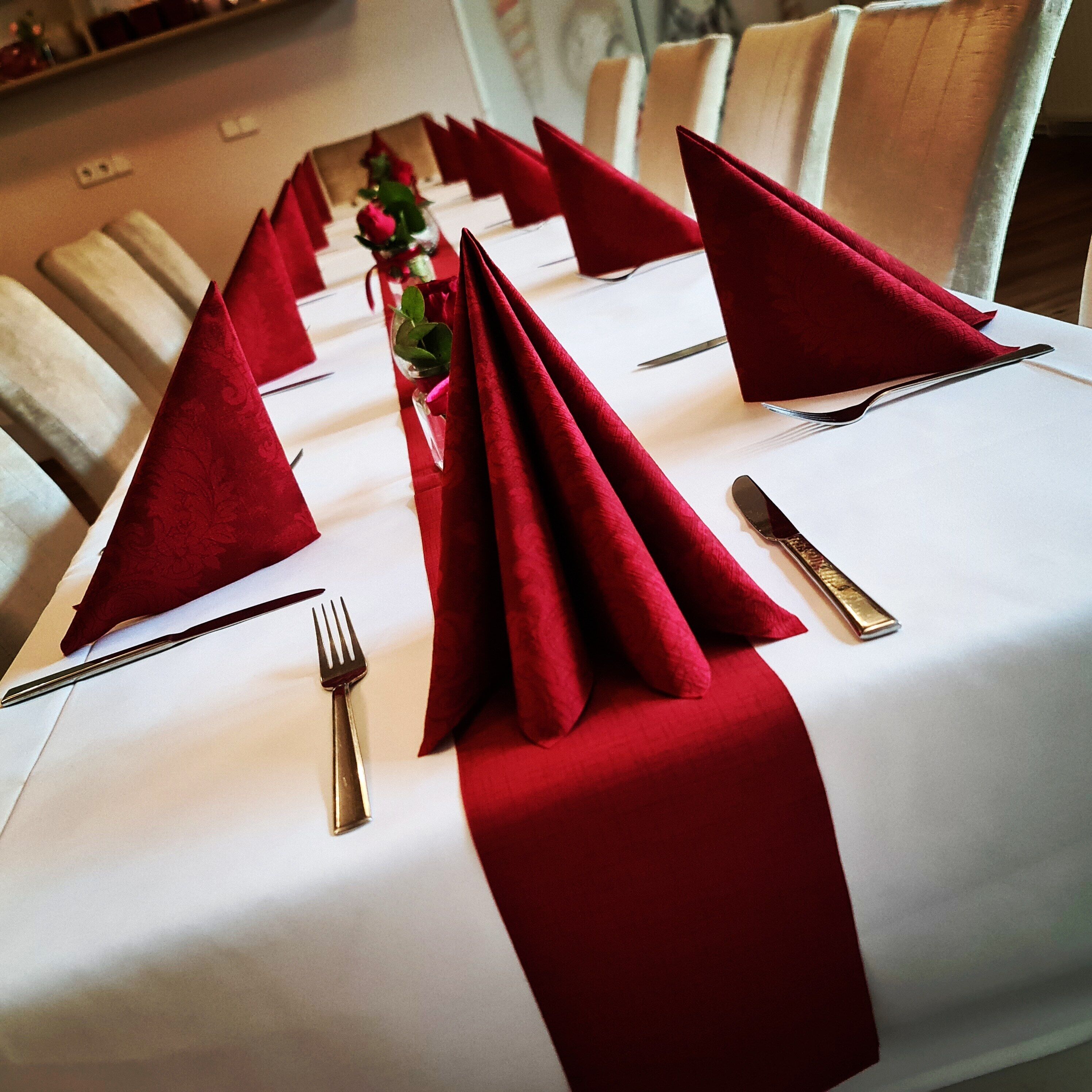 A table set with red napkins, silverware, and a glass of water.