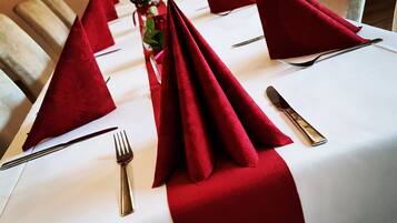 A table set with red napkins, silverware, and a glass of water.