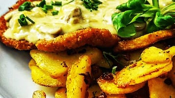 A plate with a breaded cutlet, mashed potatoes, and a green garnish.