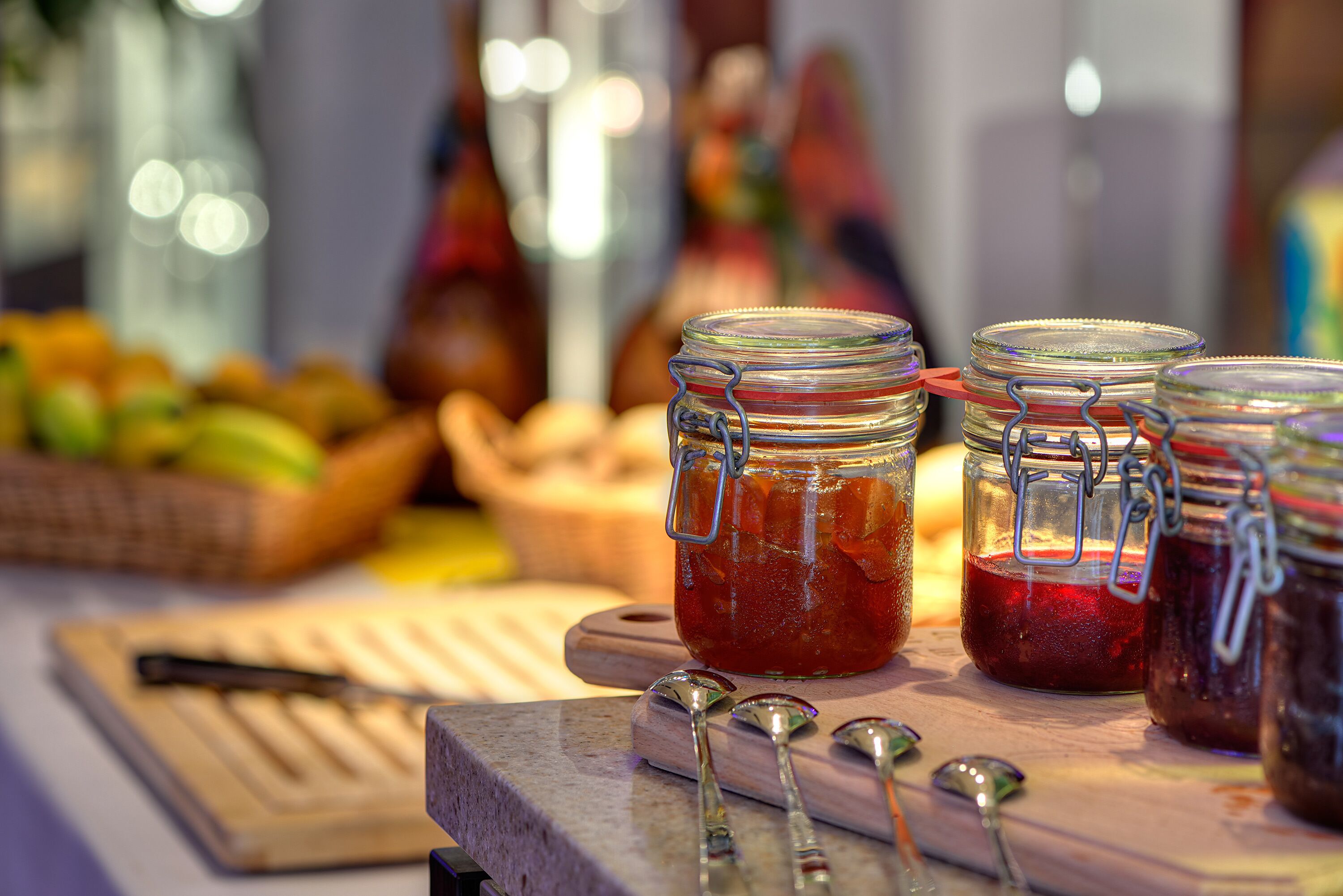 Ein Tisch mit Glaskolben, die verschiedene Marmeladen und Konserven enthalten, ein Schneidebrett und ein Messer.