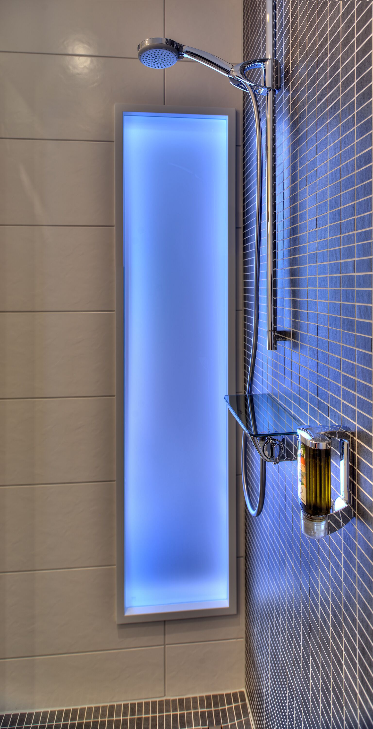 A modern bathroom with a glass-enclosed shower, a handheld showerhead, and a wall-mounted faucet.