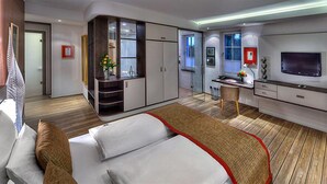 Ein modernes Hotelzimmer mit Bett, Schreibtisch, Fernseher und Kleiderschrank.
