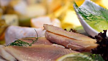 A close-up of various seafood items, including slices of fish and a bowl of salad with dill.
