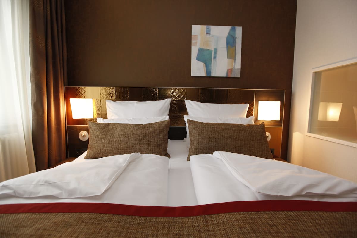 Ein Hotelzimmer mit einem großen Bett, zwei Nachttischen und einem Wandbild.