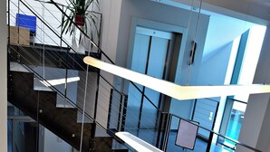 Ein modernes Interieur mit einer mehrstöckigen Treppe, einem Blumentopf und einer Tür im Hintergrund.