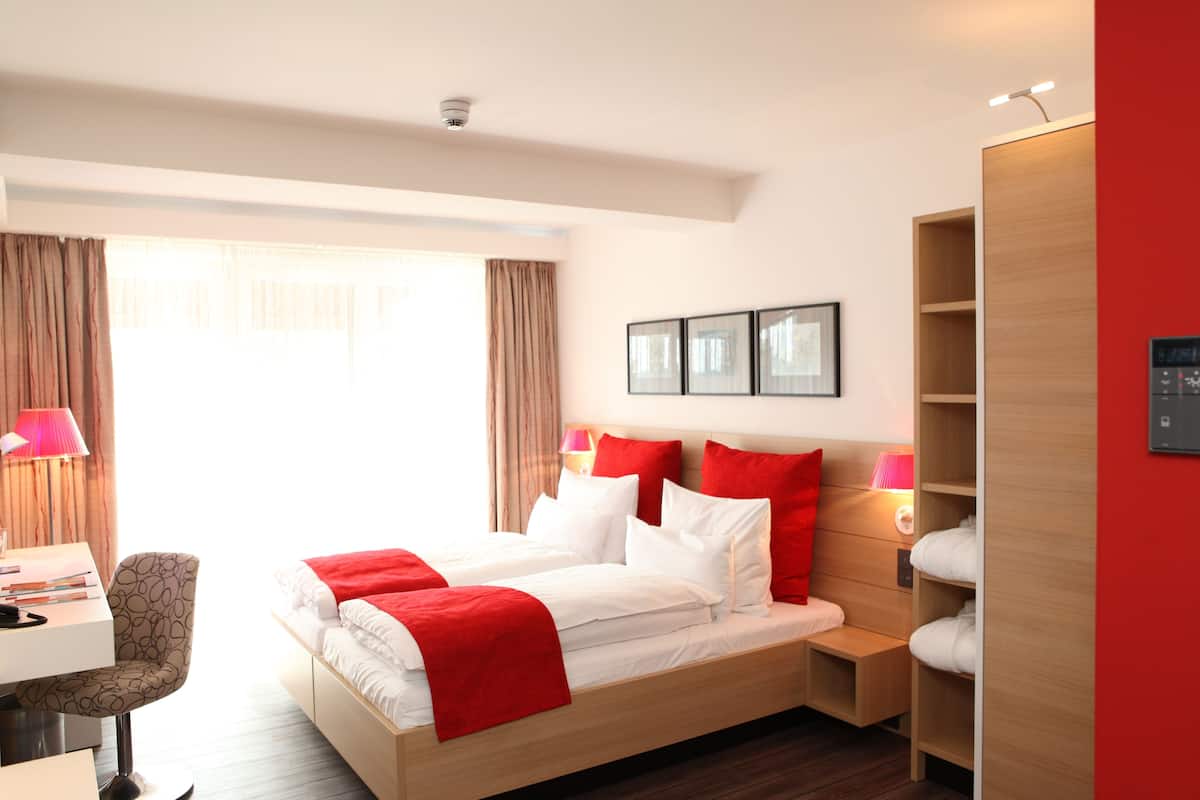 Ein Hotelzimmer mit Bett, Nachttischen, Schreibtisch und Stuhl.