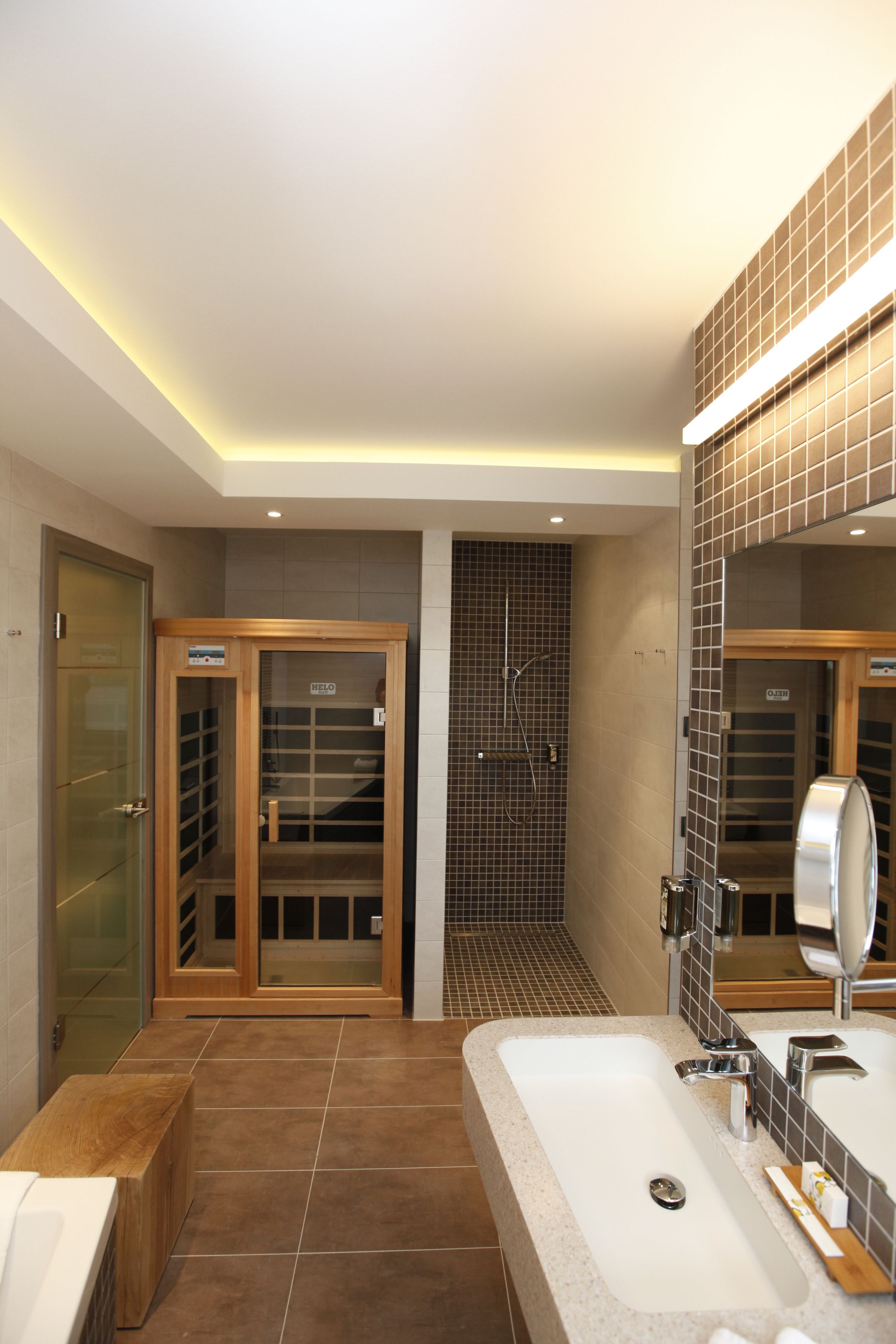 A modern bathroom with a large sink, mirror, and shower area.