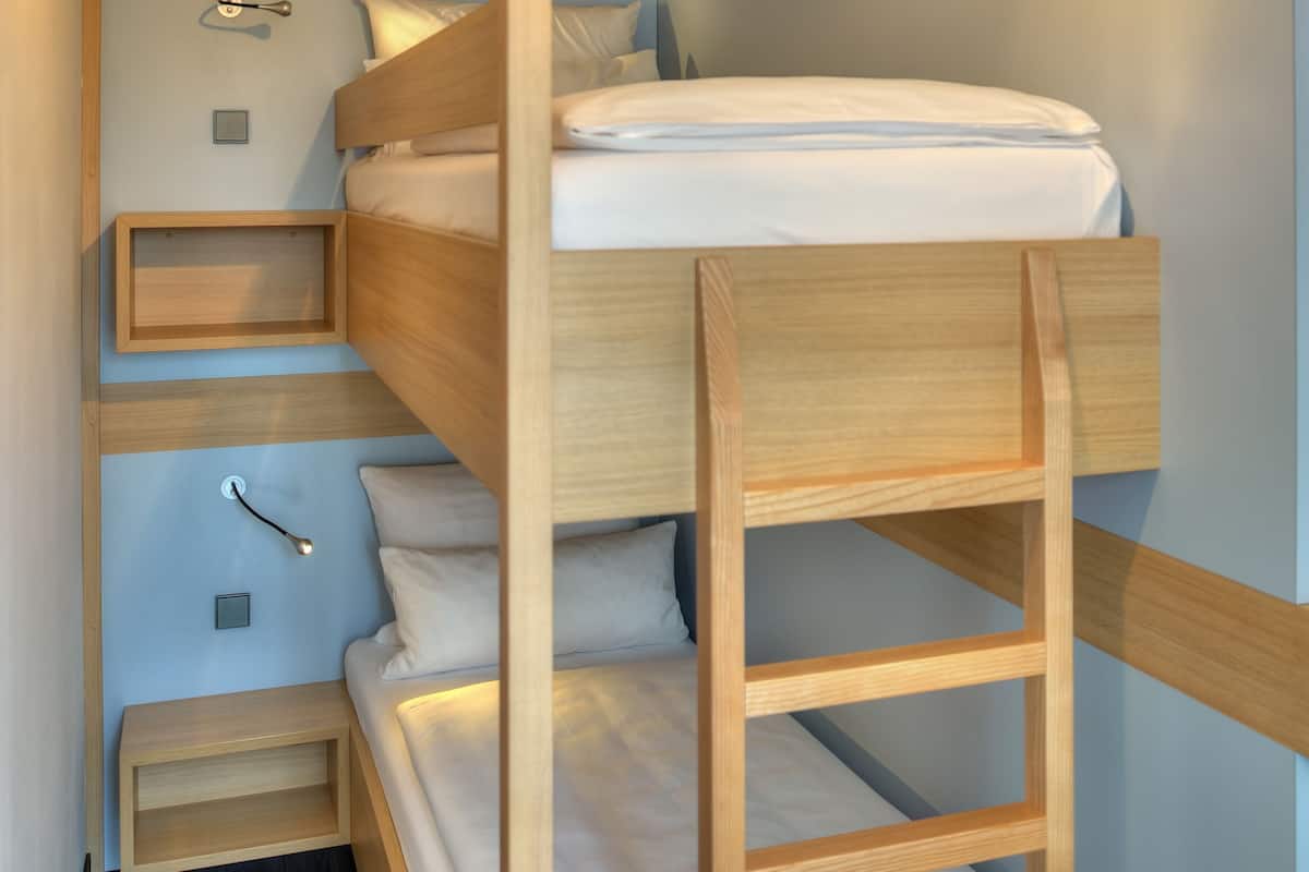 Ein Stockbett mit Holzlade, ein Nachttisch und eine kleine Ablagefläche.