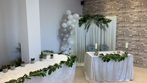 Una habitación con una mesa blanca, una pared de ladrillo y un arco de globos.