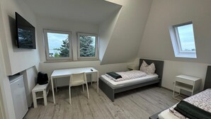 Un dormitorio con cama, escritorio y dos ventanas.