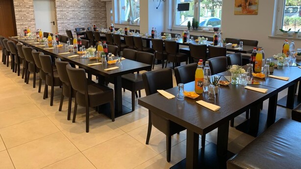Un comedor con mesas largas, sillas y diversas bebidas.