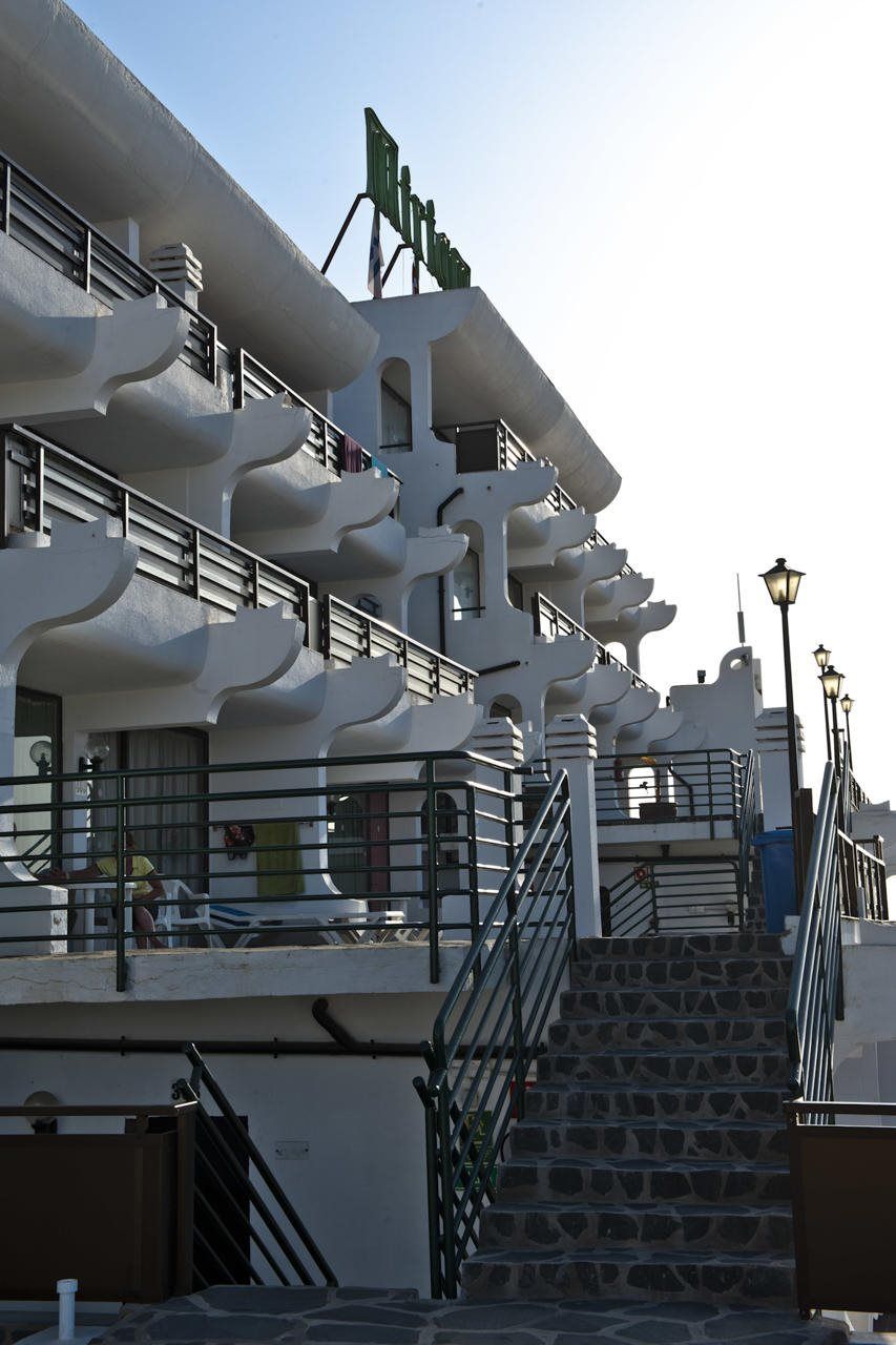 Un edificio con un diseño arquitectónico singular, con balcones con forma de olas y una escalera que lleva a la entrada.