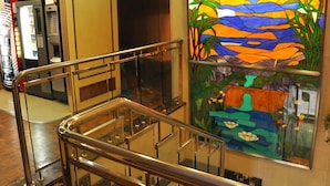A glass-walled staircase with metal railings, leading to a lower level. - Hotel Reyes Catolicos (Salamanca)